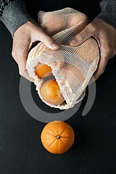 Man and reusable mesh bag with oranges
