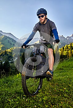 Man ride mountain bike at the green hill in the mountain of Kazakhstan