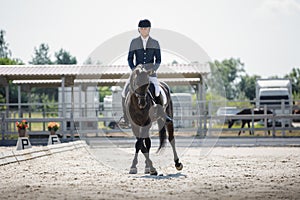 Man rider and black stallion eventing horse trotting leg-yield during equestrian dressage competition