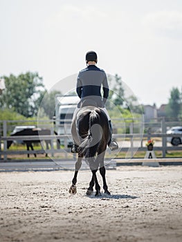 Man rider and black stallion eventing horse trotting leg-yield during equestrian dressage competition