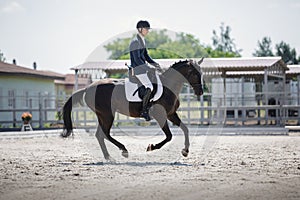 Man rider and black stallion horse galloping during equestrian dressage competition