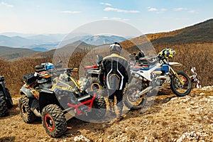 Man rider standing near Atv cars and motocross bike in mountains