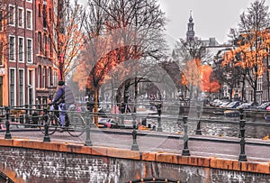 Man rides a bike on the bridge over the Amsterdam canal. Daytime