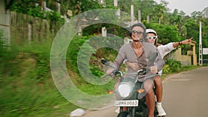 Man rides on motorbike. Woman hugs boyfriend, pointing finger. Ride on scooter in tropics. Couple in love drive