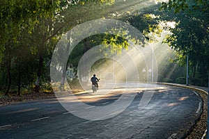 A man rides a motorcycle down a road with trees in the background