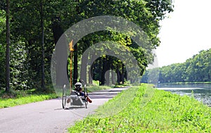 Man rides a recumbent bicycle along the water.