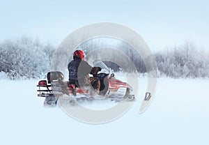 Man rides a snowmobile through the snowdrifts in winter photo