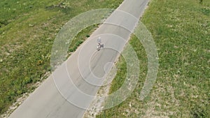 Man rides at straight road on longboard at sunset time aerial 4k. The guy rides a longboard on the way to the field, the