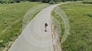 Man rides at straight road on longboard at sunset time aerial 4k. The guy rides a longboard on the way to the field, the