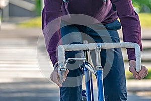 A man rides to work on a bicycle in the city. Close-up hands on the steering wheel