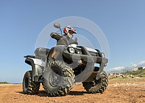 A man riding ATV in sand in a helmet.