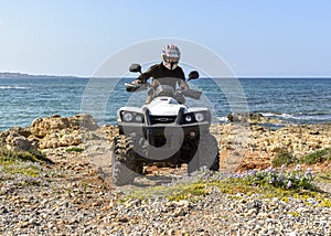 A man riding ATV in sand in a helmet.