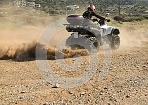 A man riding ATV in sand in a helmet.