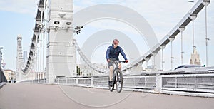 Man riding on bicycle across the bridge in the city.