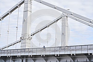 Man riding on bicycle across the bridge in the city.