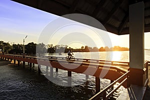 Man riding bicycle on the bridge with beautiful sunset