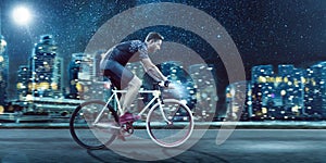 Man Riding a Bicycle in Front of a City Skyline at Night