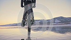 Man is riding a bicycle on ice. The cyclist is dressed in a gray down jacket, backpack and helmet. Ice of the frozen