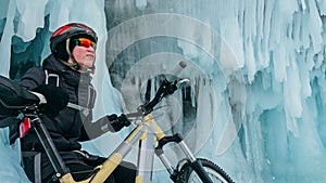 Man is riding bicycle near ice grotto. Rock with ice caves icicl