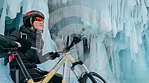 Man is riding bicycle near ice grotto. Rock with ice caves icicl photo