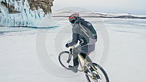 Man is riding bicycle near ice grotto. Rock with ice caves icicl photo