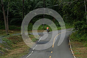 Man riding a bicycle on a pathway surrounded by trees in Thailand