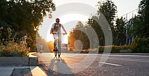 Man is riding on bicycle on the street on the sunset.