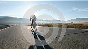 Man riding a bike on asphalt road towards the sunny sunset sky 20s 4k.