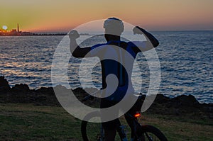 Man riding bike in front of the sea during sunrise