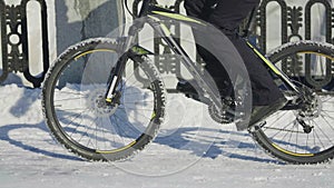 Man riding a bike on a snowy day, slippery road conditions. Close up of a man's feet pedaling. Courier delivery of food