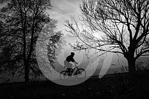 Man riding a bike uphill through foggy autumn morning