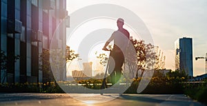 Man riding black electric kick scooter at cityscape background at sunset