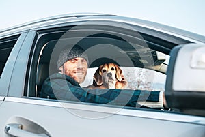 Man riding a car and his beagle dog sit inside near with him