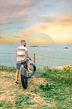 Man riding a fat bike looking at the sea from the coast