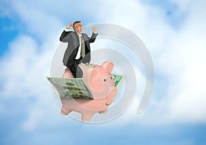 Man riding flying piggy bank on wings of money showing financial and business success