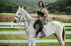 Man riding horse. Hunky cowboy. Young muscular guy in t-shirt on horseback. Sexy male torso.
