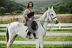 Man riding horse. Hunky cowboy. Young muscular guy in t-shirt on horseback. Sexy male torso. photo