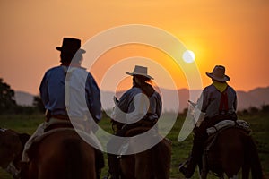 Silhouette of two western riders against amber colored sunset