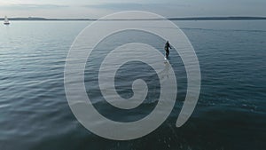 Man riding on a hydrofoil surfboard on large blue lake in sunny weather