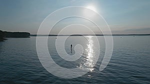 Man riding on a hydrofoil surfboard on large blue lake in sunny weather