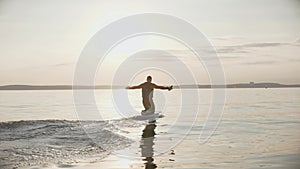 Man riding a hydrofoil surfboard on large lake at golden sunset sitting on knees