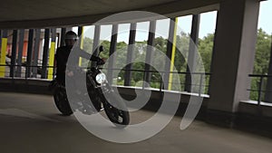 Man riding motorbike turning on the corner of the multi-level parking