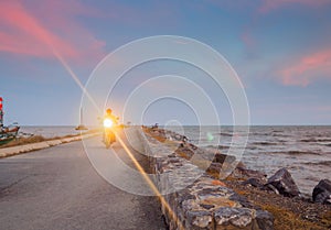 A man riding motorcycle with headlight on, at the pier