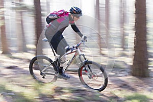 Man riding a mountain bike in a forest on a sunny day with fog