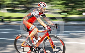 Man riding orange racing bike on road blurred background