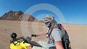 Man is riding a quad bike in desert of Egypt and shooting himself on an action camera