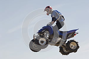 Man Riding Quad Bike In Midair Against Sky photo