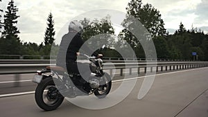 Man riding scrambler motorbike on the highway through the autumn forest