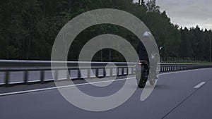 Man riding scrambler motorbike on the highway through the autumn forrest