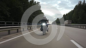 Man riding scrambler motorbike on the highway through the forest, front view